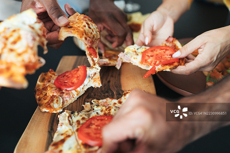 一群朋友在一起享受美好时光，传递和分享食物的特写镜头。图片素材