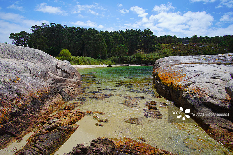 宁静的海岸风景，岩石海岸线和森林覆盖的山丘，西班牙阿罗萨岛图片素材
