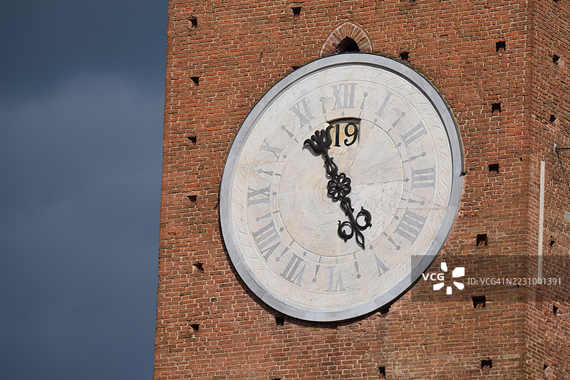 意大利砖塔上的大型钟面与黑暗的天空图片素材