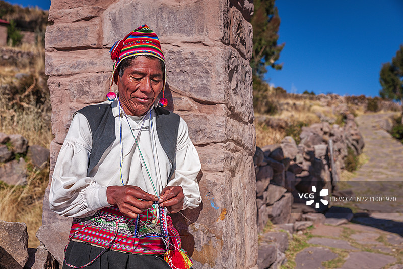 在秘鲁的的的喀喀湖塔基莱岛上，一名男子正在编织帽子。图片素材