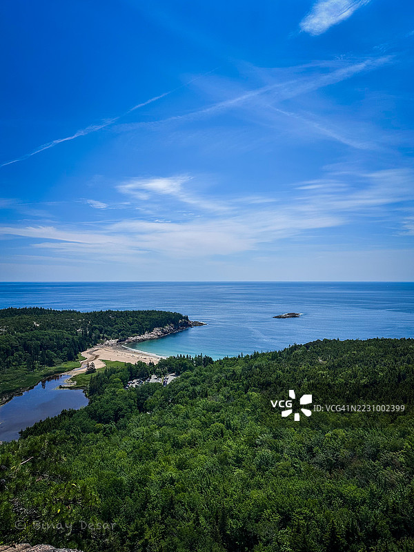 郁郁葱葱的森林和海岸线在蔚蓝的天空下的鸟瞰图图片素材