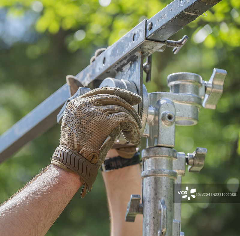 舞台工作人员在户外活动搭建中调整金属桁架支撑结构图片素材