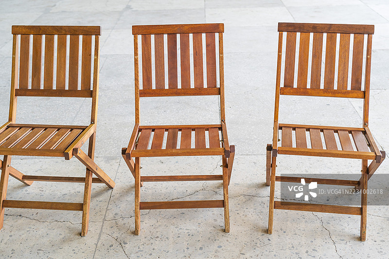 三把空的折叠木椅放在混凝土地面上图片素材