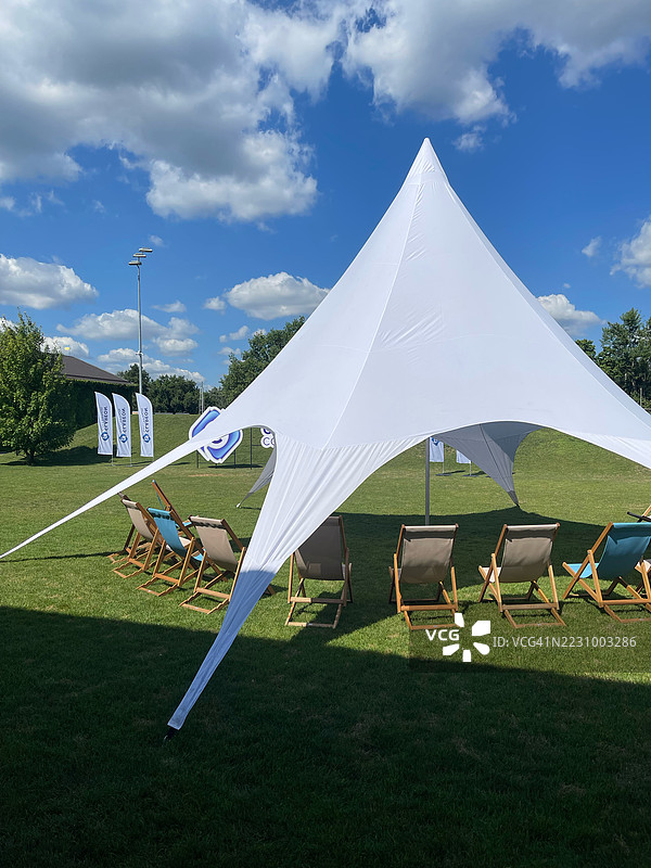 蓝天下草地上的大型白色帐篷和躺椅图片素材