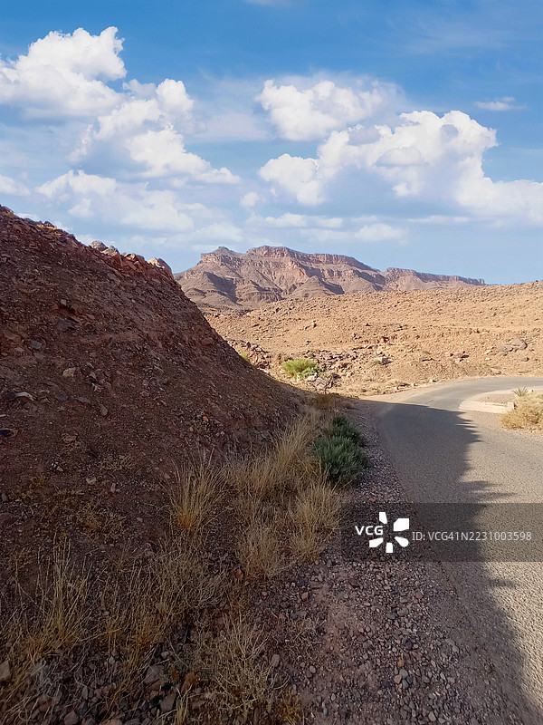 摩洛哥阿格兹蓝天下蜿蜒穿过岩石山脉的沙漠公路图片素材