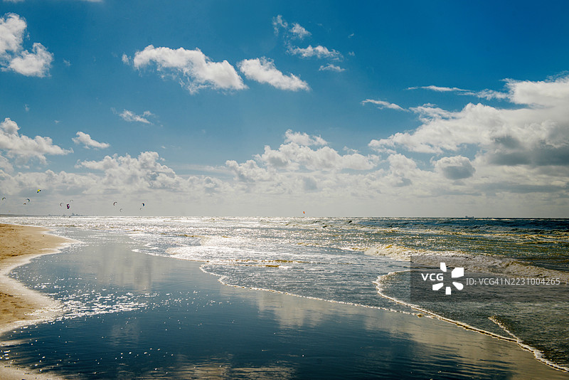 阳光明媚的海滩风景，风筝冲浪者在水面上飞驰图片素材