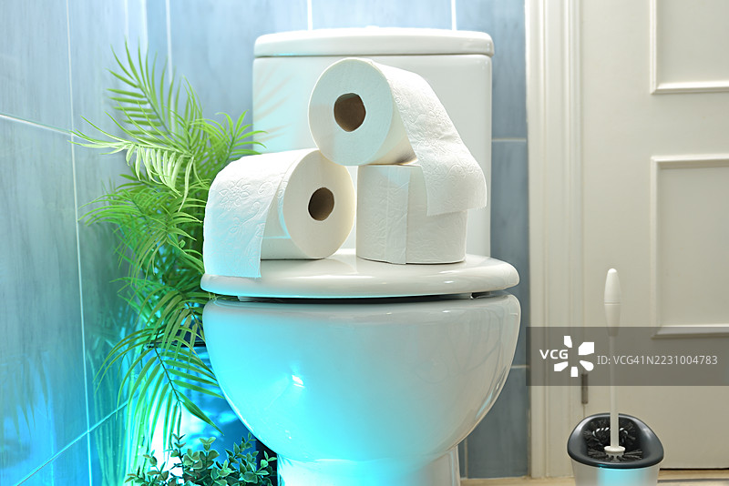 卫生间里堆叠着卫生纸卷的马桶图片素材