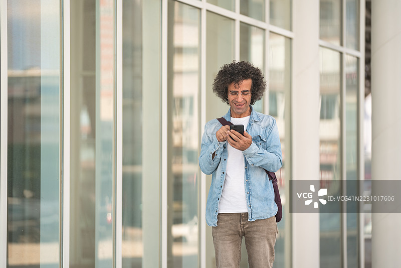 成熟男性在街上走动时使用智能手机的照片图片素材