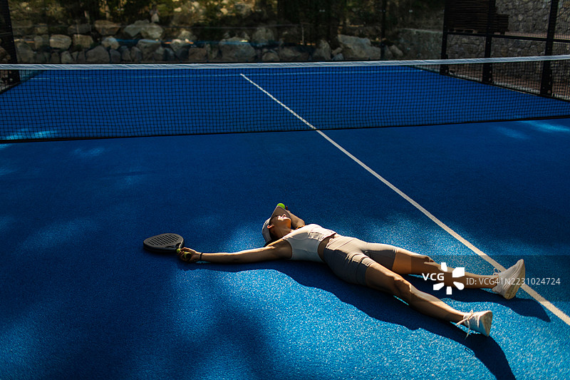 年轻女性壁球运动员在蓝色网球场上休息图片素材