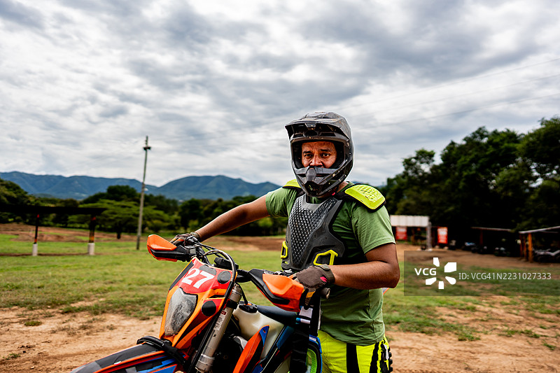 摩托越野车手在赛道旁的摩托车前的肖像图片素材