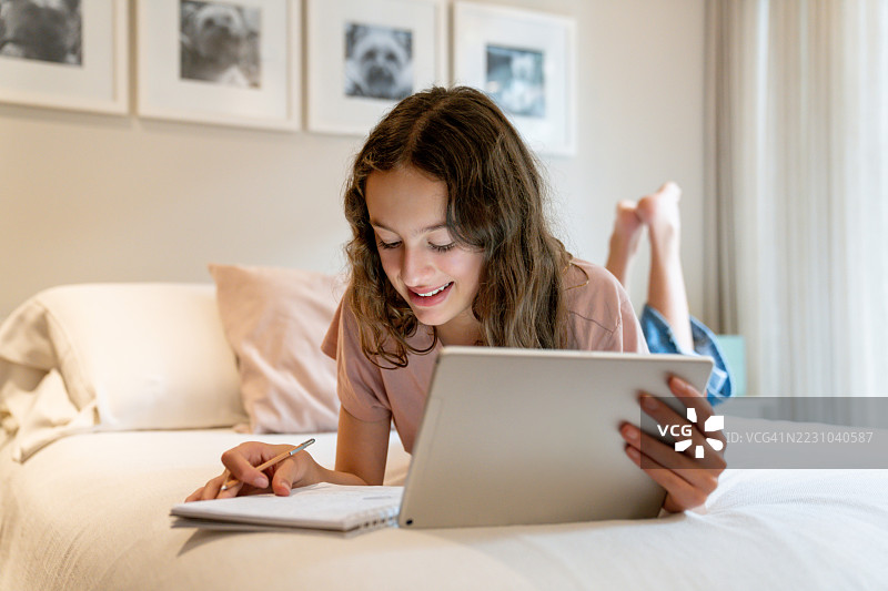 女孩在卧室里用平板电脑做作业图片素材