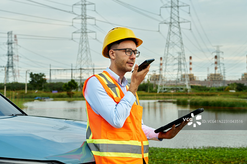 工程师在发电厂附近使用手机和平板电脑图片素材