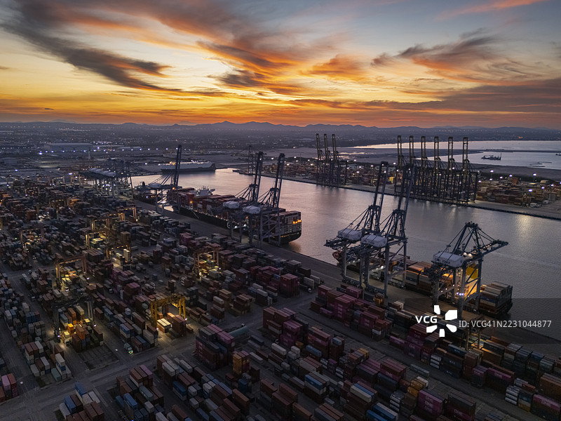 黄昏时分的商业港口或集装箱货船港口的鸟瞰图，适用于商业物流、进出口、航运或货物运输。图片素材