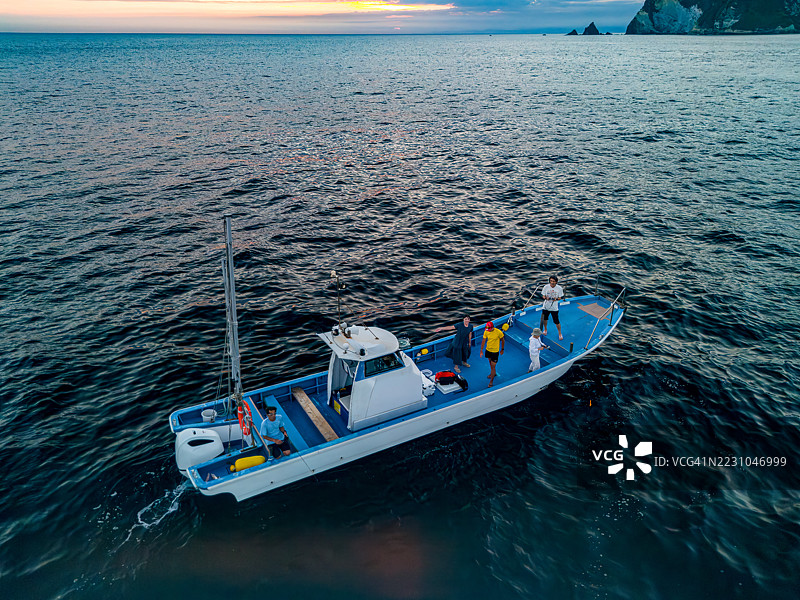 人们在船上钓鱼。无人机航拍，经过许可。正在捕捞黑鳍石斑鱼（Epinephelus fasciatus），在日落时分的渔船上。图片素材