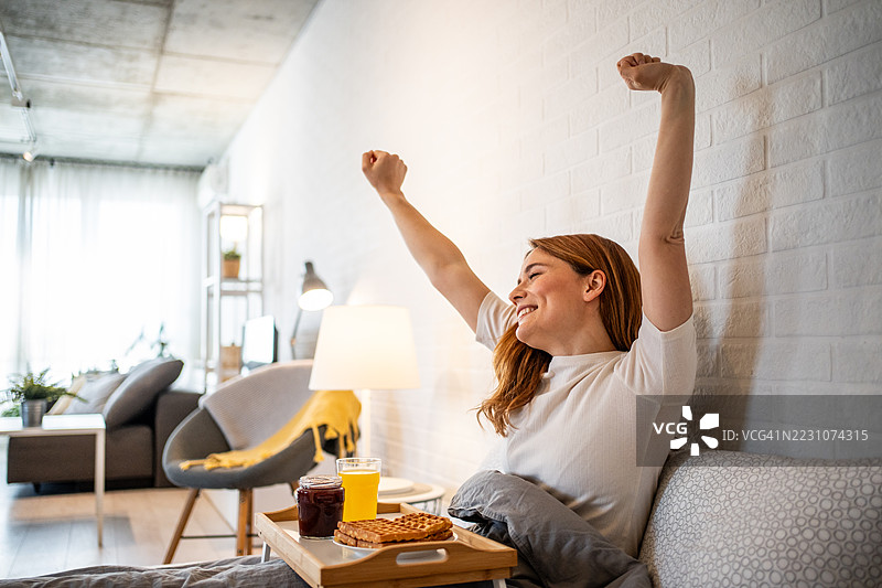 年轻女性早晨醒来后在床上伸展身体图片素材