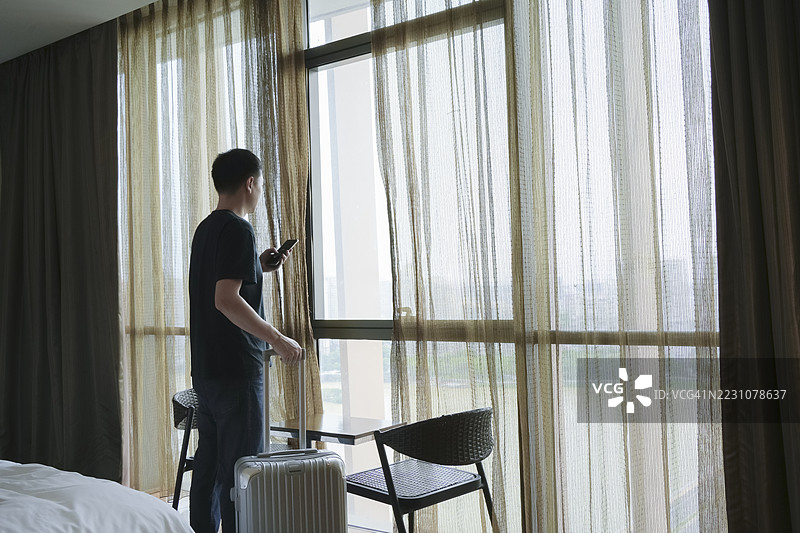 商人到达酒店房间后在窗边使用手机图片素材
