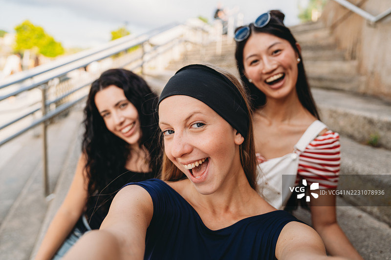 三位年轻女性坐在城市台阶上自拍图片素材