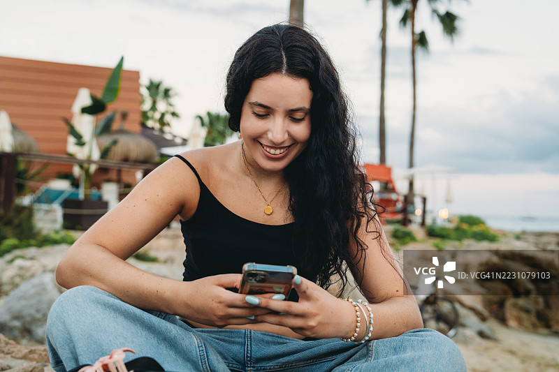 年轻女性在海滩上使用手机图片素材