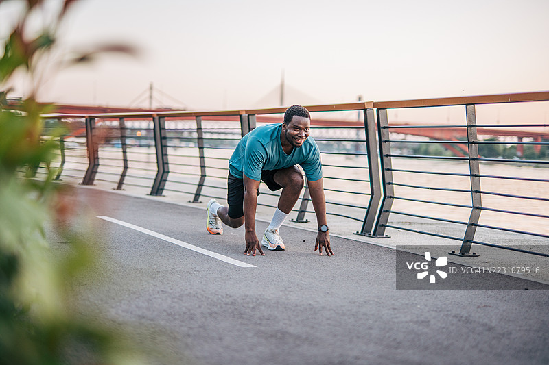 年轻男性运动员在河边准备跑步图片素材