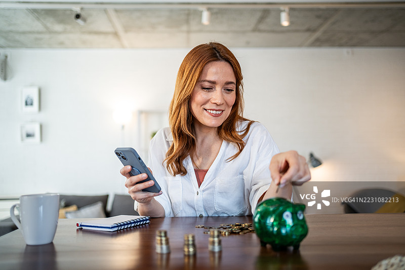 女性使用手机银行应用和储蓄罐存钱图片素材