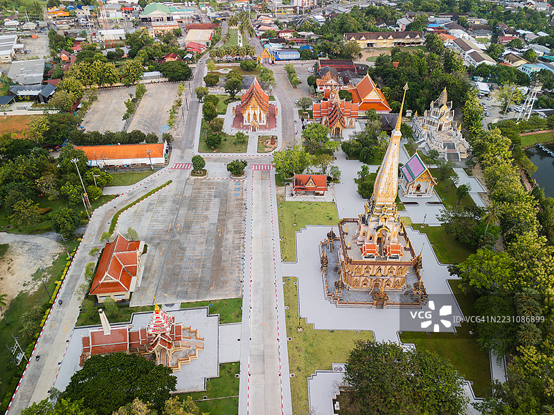 从空中俯瞰的无人机图像，展示了泰国普吉岛广阔的查龙寺庙群，金色的佛塔、步道和郁郁葱葱的绿地。图片素材