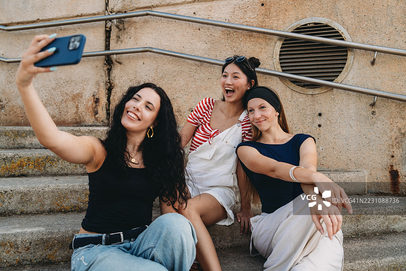三位年轻女性坐在城市台阶上自拍图片素材