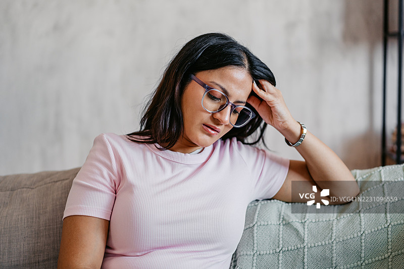 伤心的年轻印度女性坐在家里的沙发上图片素材