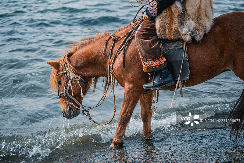 湖边穿着传统蒙古服饰的骑马者图片素材