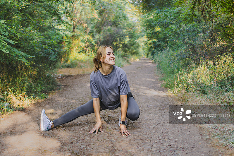 美丽的年轻女性穿着运动服，在大自然中热身或拉伸。她在锻炼过程中平衡力量与柔韧性。积极的生活方式、心理健康与健身。图片素材