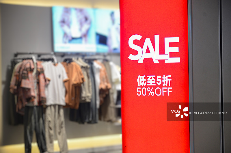 时尚服装店促销：当季服饰特卖。热闹的服装店内提供限时折扣，挂有醒目的促销标语。图片素材