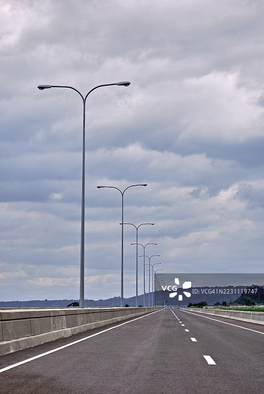 一条笔直的公路在阴云密布的天空下延伸至远方。图片素材