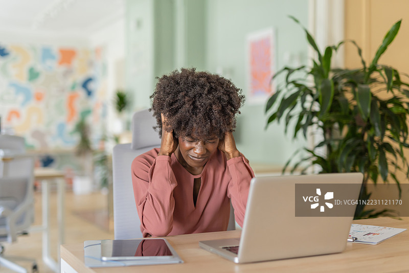 卷发女性在工作桌前挣扎于压力中图片素材