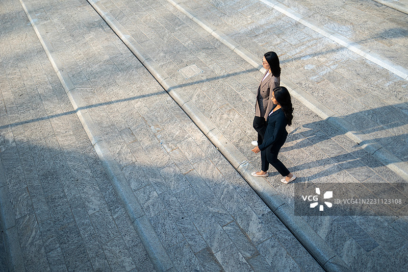 两位女商人在现代城市楼梯上走下。图片素材