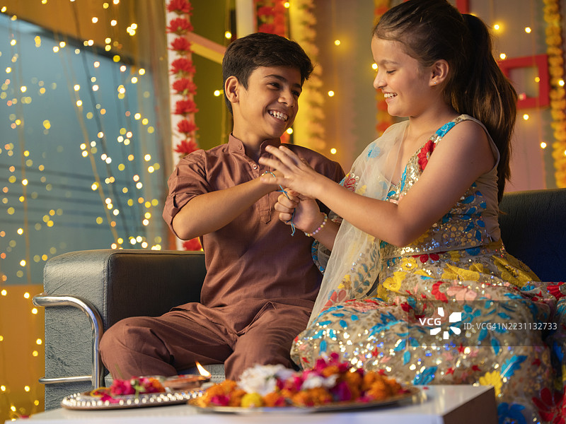 女孩在兄弟的腰间系上拉基，庆祝拉克沙班丹节。图片素材