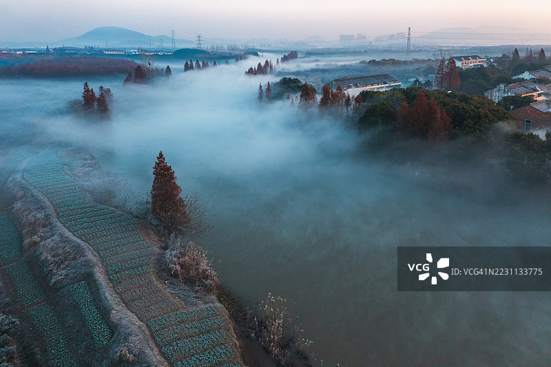清晨雾气弥漫的河流在乡村田野中蜿蜒流淌的鸟瞰图图片素材