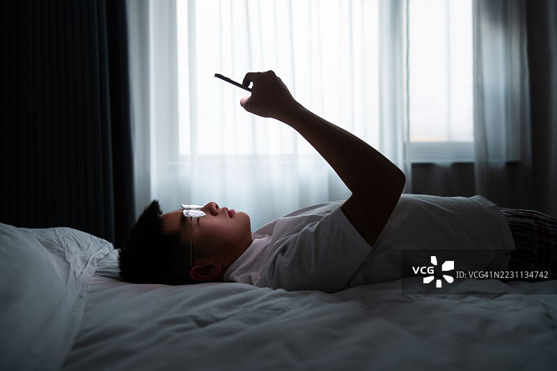 少年男孩躺在床上使用手机图片素材