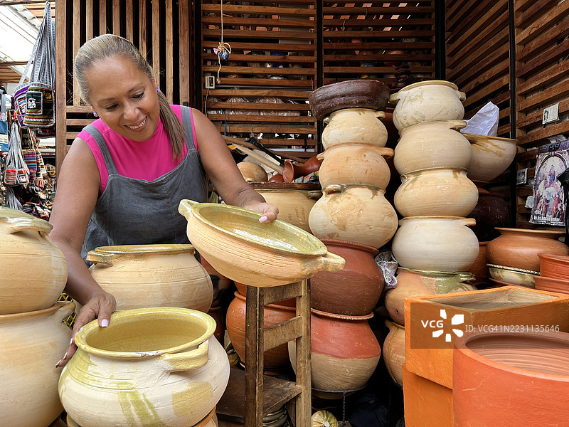 厄瓜多尔库恩卡的非洲裔成熟工匠展示手工陶器 // 快乐的非洲裔女性背包客在厄瓜多尔库恩卡的街市上购买纪念品图片素材