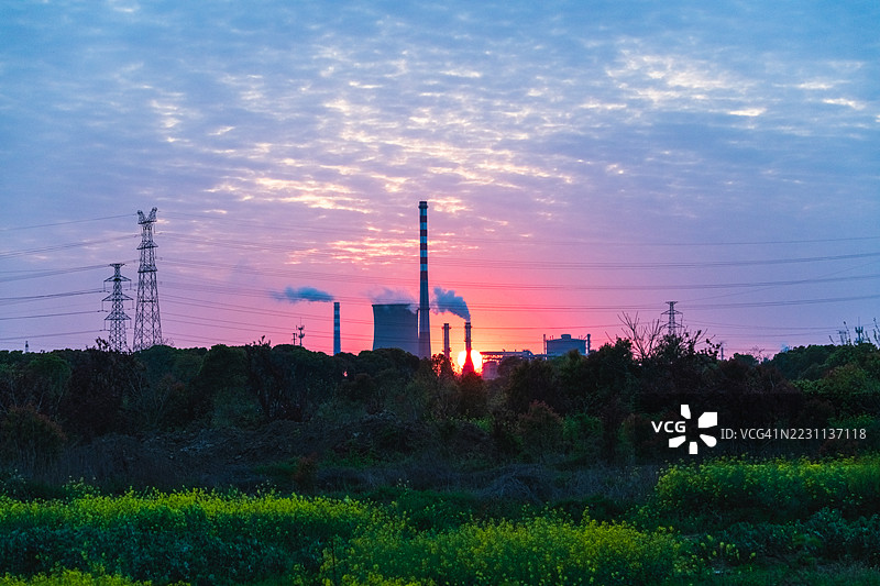 工业电厂的日落景观与绿色田野图片素材