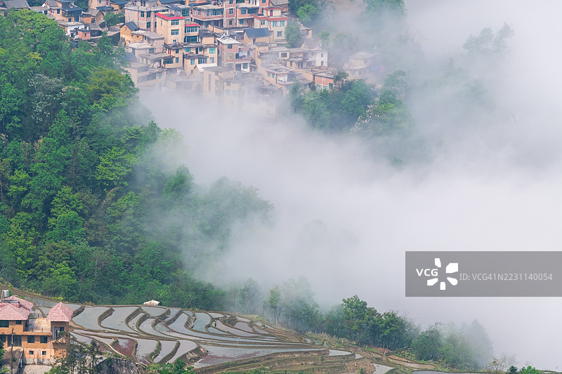 被雾气环绕的山地梯田和村庄图片素材