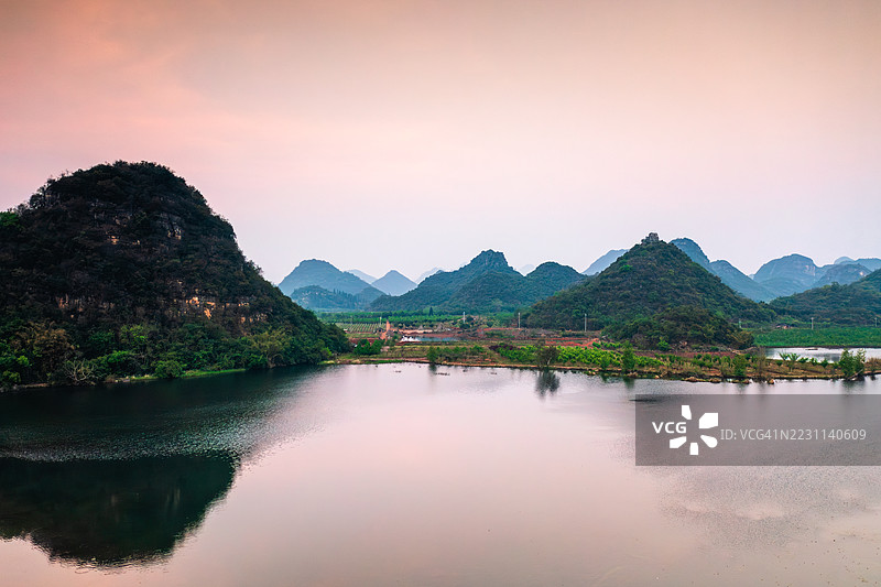 喀斯特山脉和宁静湖泊的日落美景图片素材