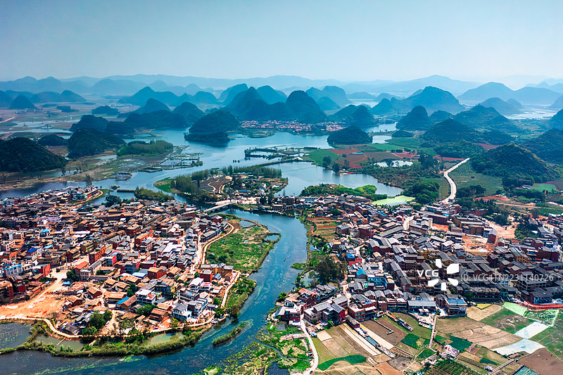 河流和喀斯特山丘环绕的风景如画的村庄鸟瞰图图片素材