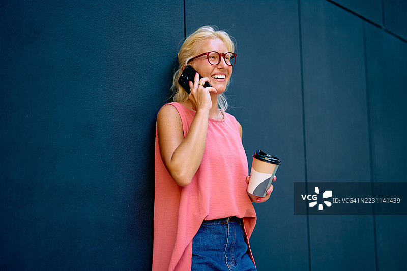 微笑的女商人一边打电话一边拿着咖啡图片素材