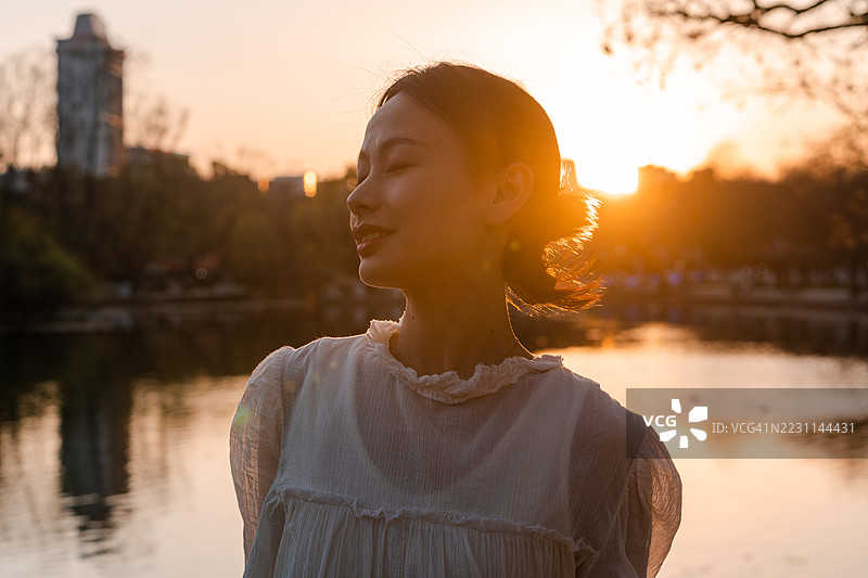 年轻亚洲女性在日落时分站在城市的侧面视图图片素材