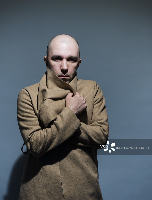 神秘的光头男人握着外套领子，面露威胁之色图片素材