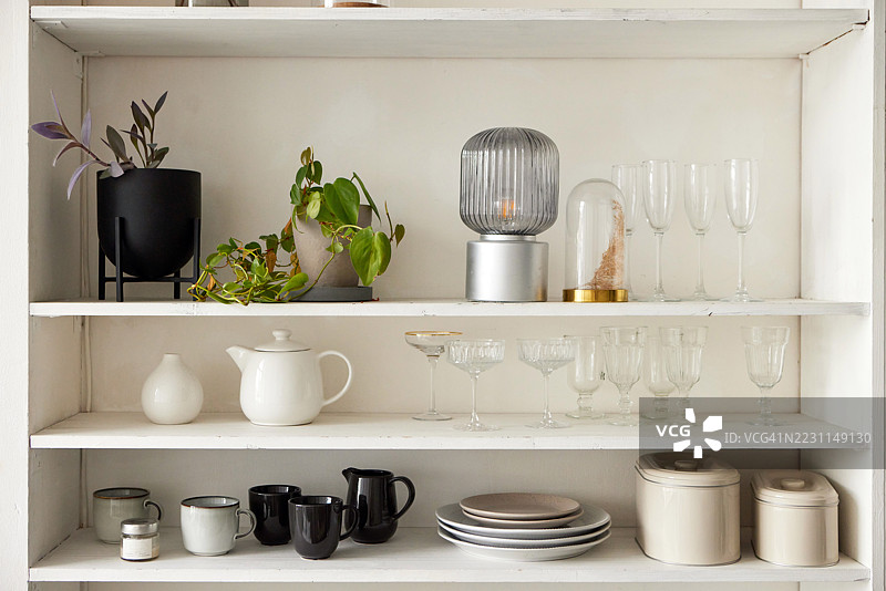 现代白色书架展示家居用品、餐具和植物，营造出时尚而有序的空间图片素材