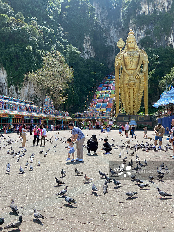 游客在吉隆坡的穆鲁根神雕像前喂鸽子。图片素材