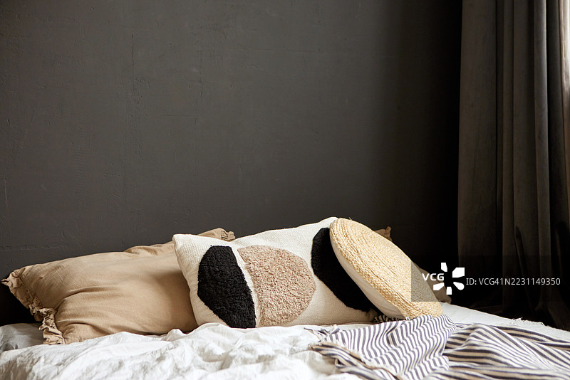 现代卧室室内设计，配有装饰性抱枕和深色墙壁图片素材