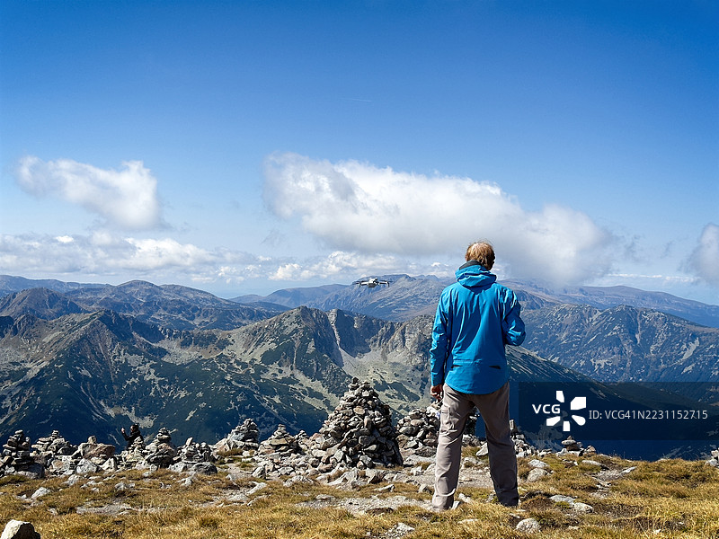 中年男子背对着山脉，操控无人机拍照，保加利亚图片素材