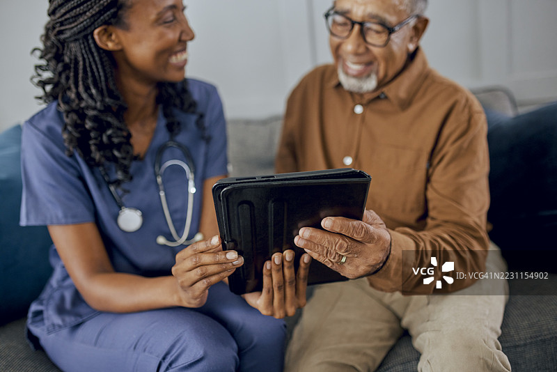 年轻护理人员与老年男性一起查看数字平板电脑的特写镜头图片素材
