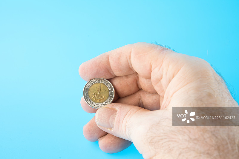 手持一枚埃及1镑图坦卡蒙法老硬币。图片素材